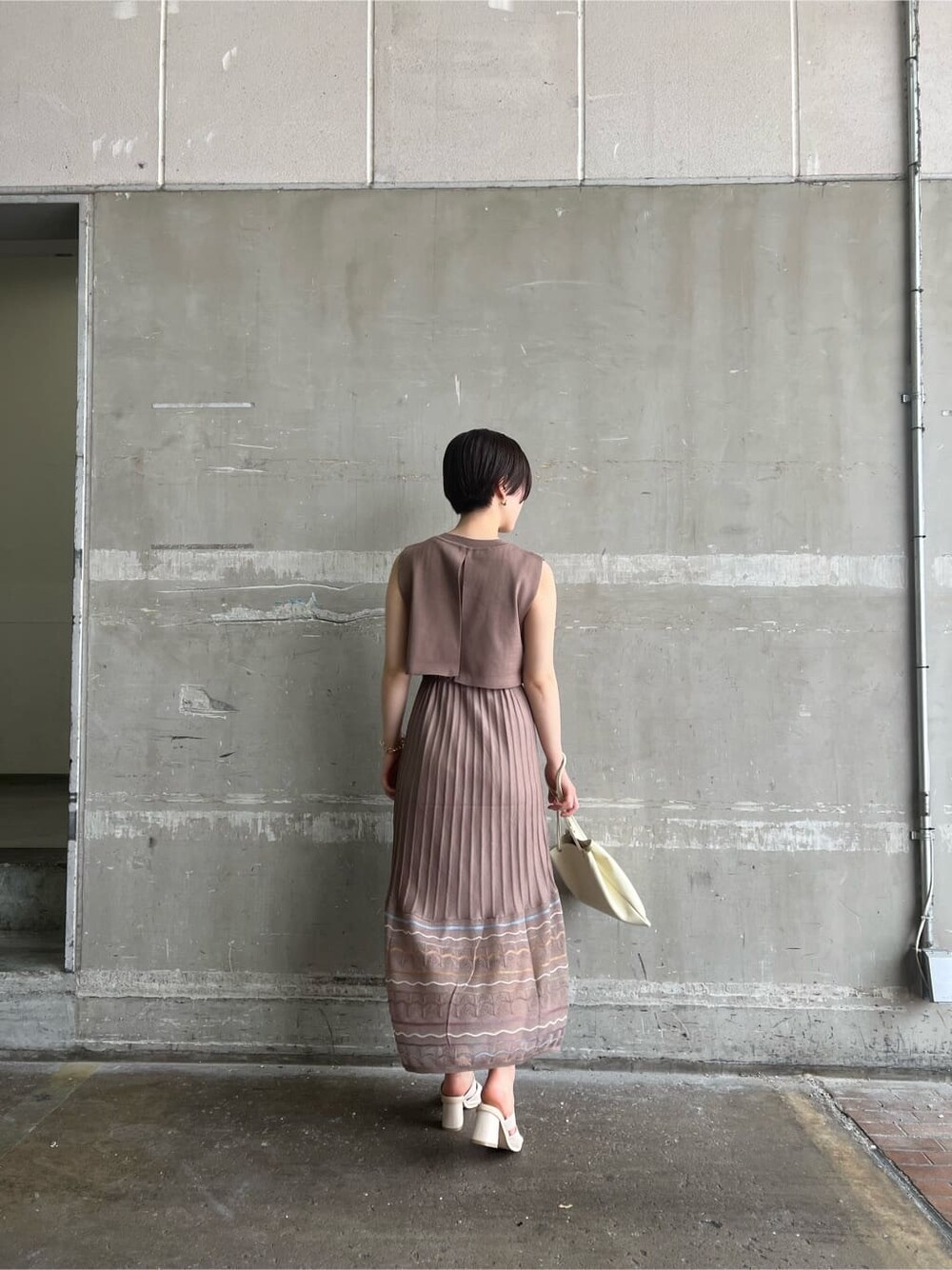 ホワイト系のハンドバッグ、ホワイト系のサンダル、ブラウン系のワンピースを着用したレディースの夏コーディネートの3枚目の写真