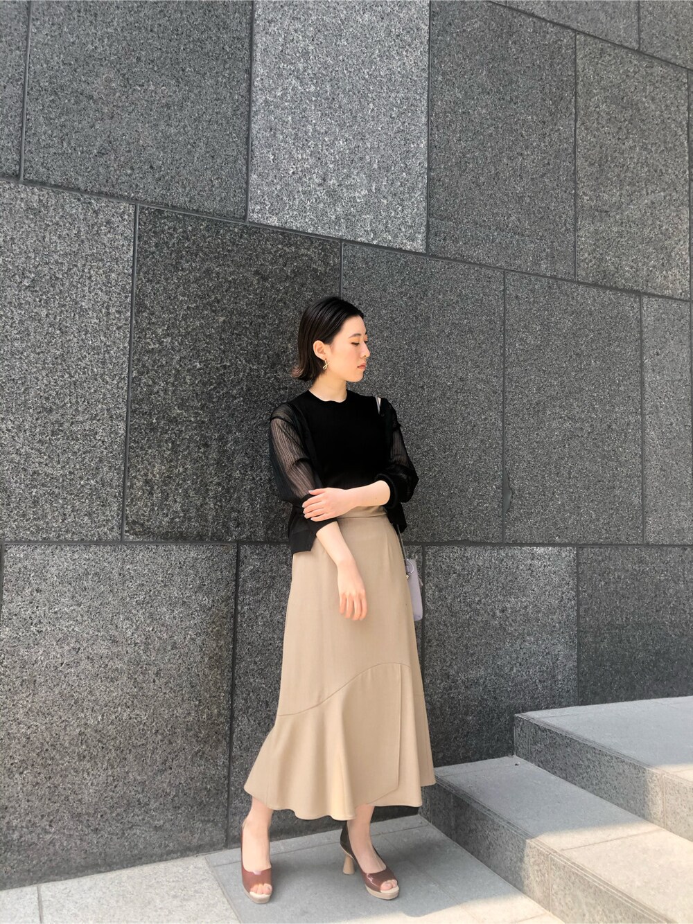 ブラック系のニット/セーター、ブラウン系のパンプス、パープル系のハンドバッグを着用したレディースの春コーディネートの2枚目の写真