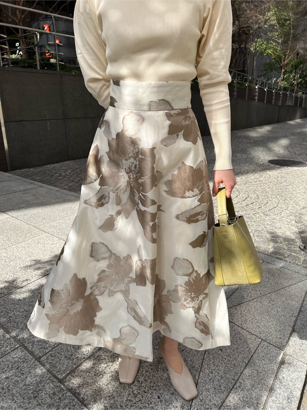 イエロー系のその他アウター、ベージュ系のスカート、ホワイト系のニット/セーターを着用したレディースの冬コーディネートの3枚目の写真