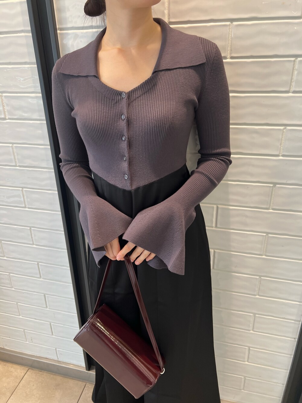 レッド系のショルダーバッグ、ブラック系のブーツ、グレー系のワンピースを着用したレディースの秋コーディネートの4枚目の写真