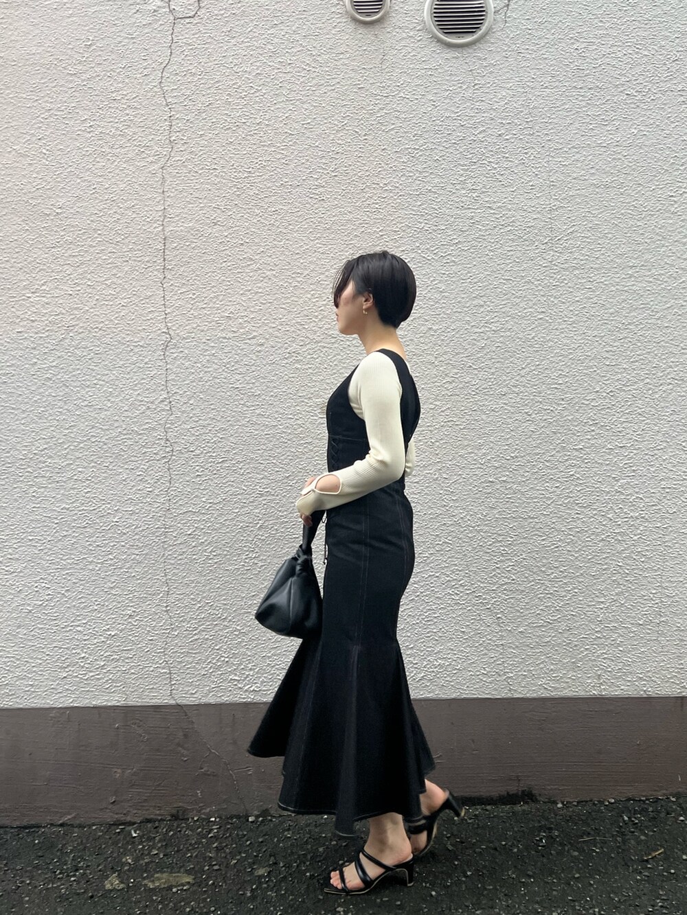 ブラック系のハンドバッグ、ブラック系のワンピース、ホワイト系のニット/セーターを着用したレディースの秋コーディネートの2枚目の写真