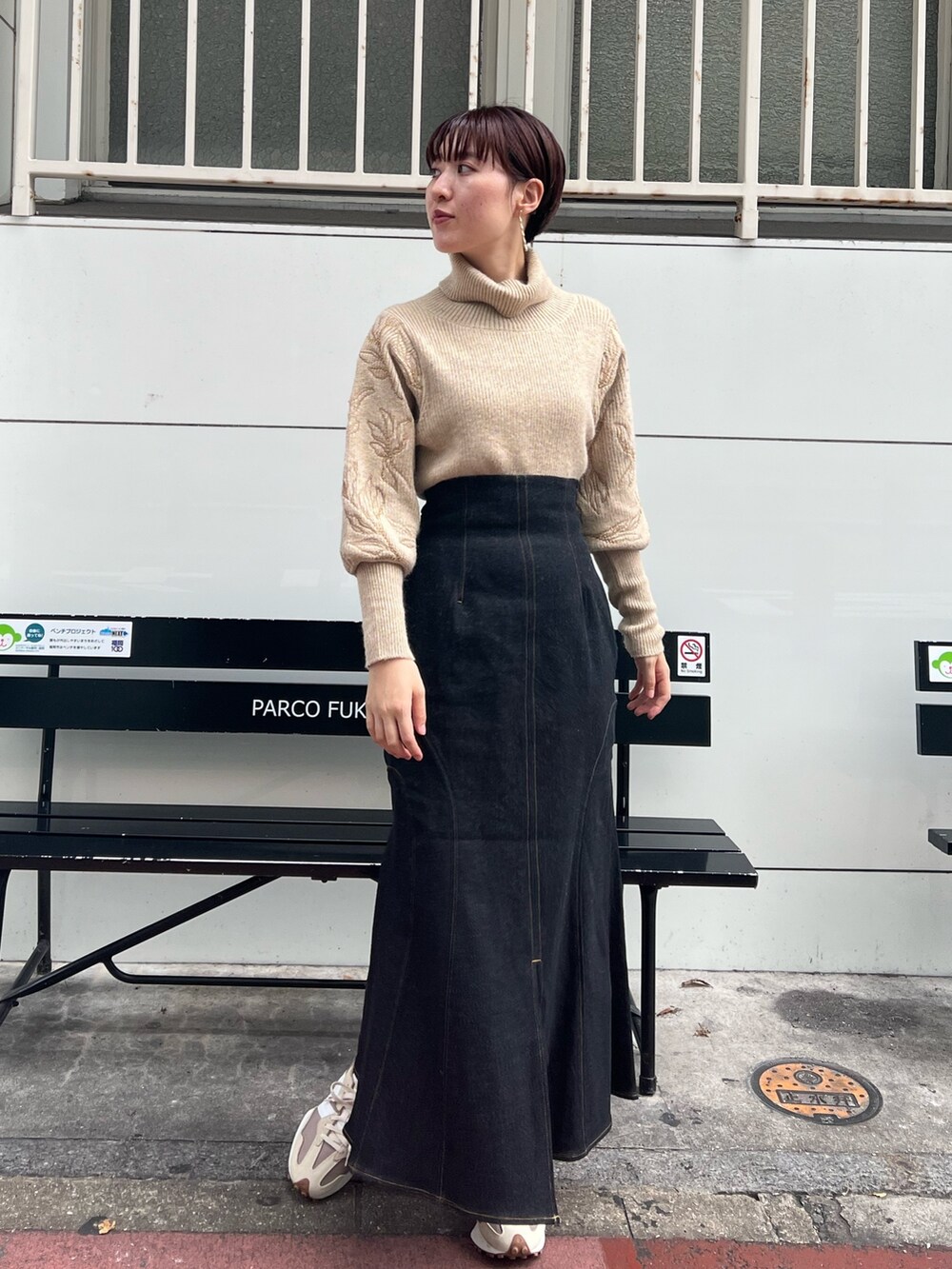 ベージュ系のスニーカー、グリーン系のカーディガン/ボレロ、ブラック系のデニムスカートを着用したレディースの秋コーディネートの6枚目の写真