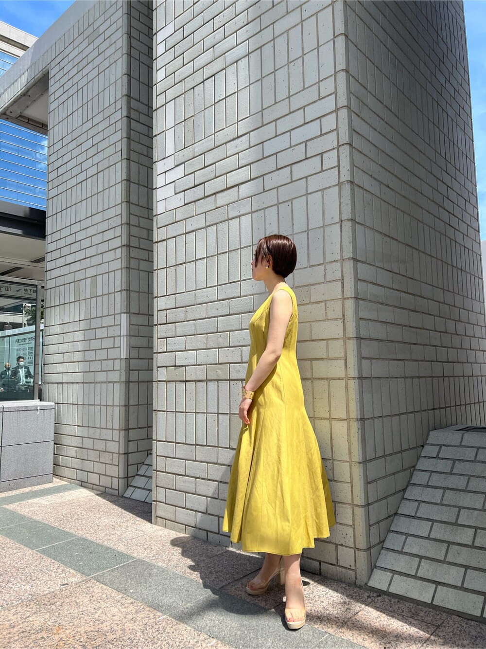 その他のパンプス、イエロー系のワンピース、ゴールド系のバングル/リストバンドを着用したレディースの春コーディネートの7枚目の写真