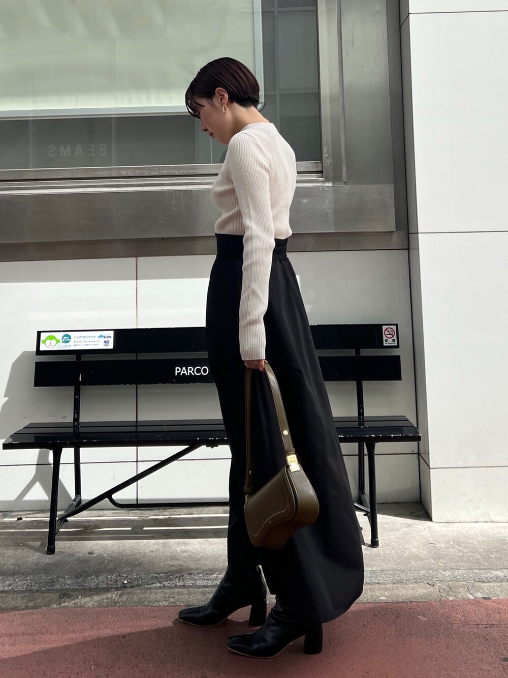 ホワイト系のニット/セーター、ブラック系のブーツ、ブラック系のスカートを着用したレディースの秋コーディネートの2枚目の写真