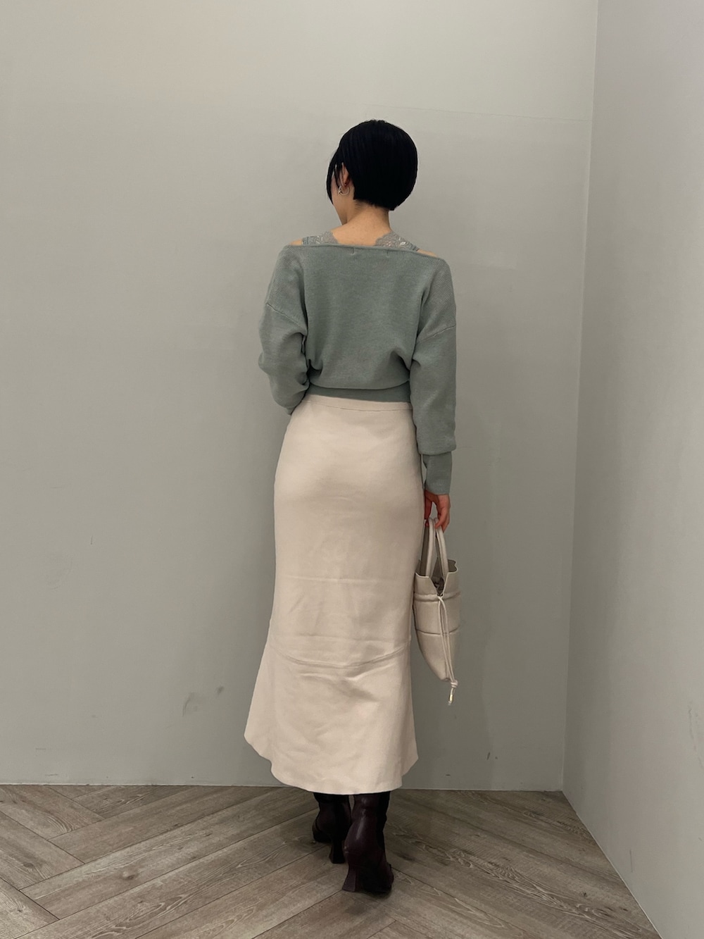 レッド系のブーツ、ホワイト系のハンドバッグ、ホワイト系のスカートを着用したレディースの冬コーディネートの3枚目の写真