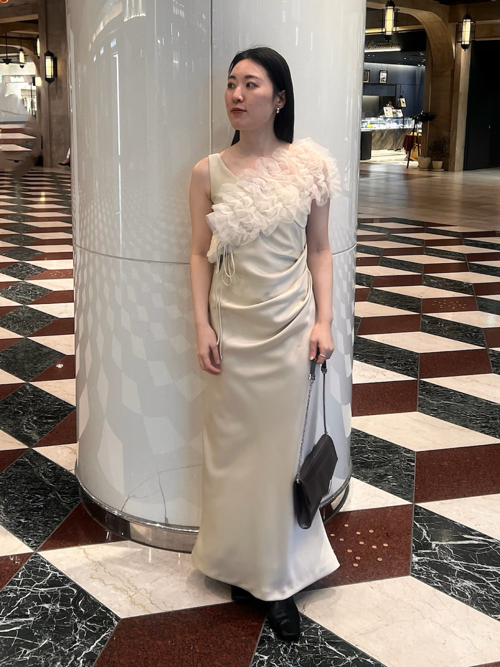 グレー系のテーラードジャケット、イエロー系のドレス、シルバー系のクラッチバッグを着用したレディースの冬コーディネートの4枚目の写真