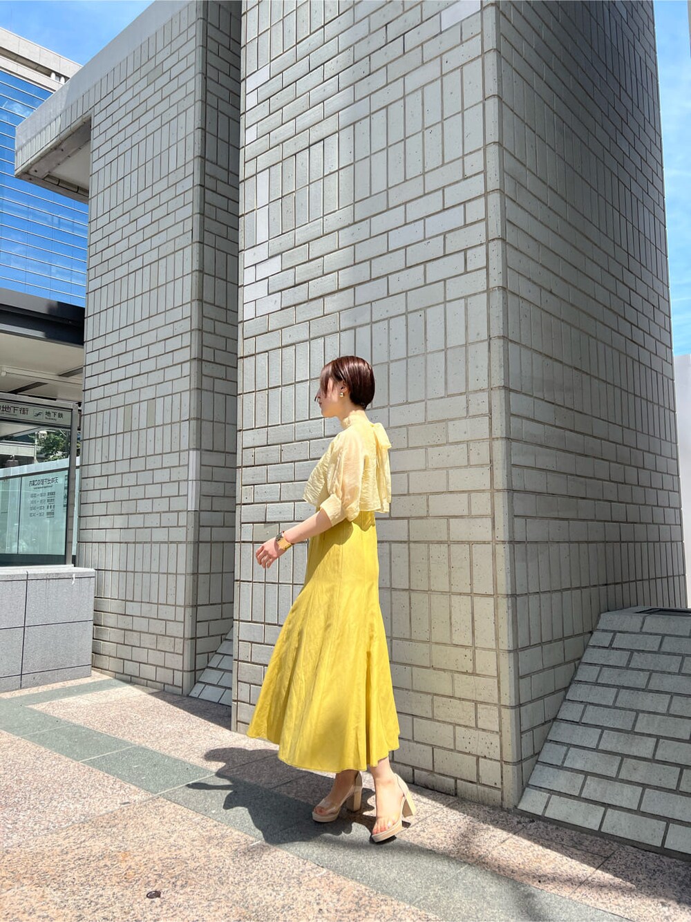 その他のパンプス、イエロー系のワンピース、ゴールド系のバングル/リストバンドを着用したレディースの春コーディネートの2枚目の写真