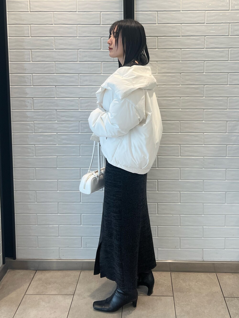 ホワイト系のダウンジャケット/コート、ブラック系のワンピース、ブラック系のブーツを着用したレディースの冬コーディネートの2枚目の写真