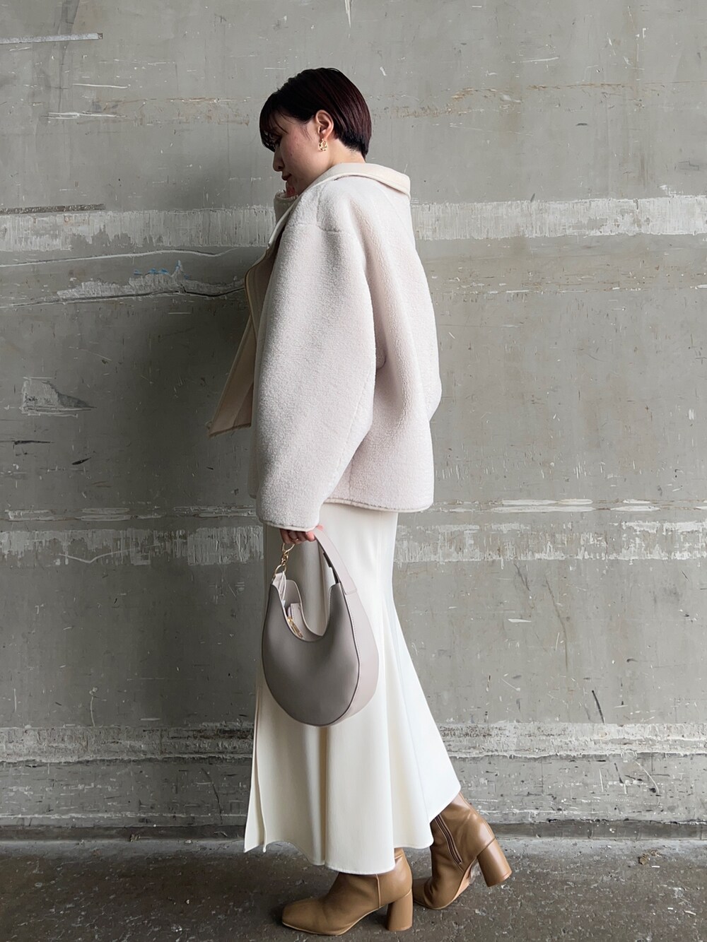ベージュ系のブーツ、ホワイト系のハンドバッグ、ホワイト系のムートンコートを着用したレディースの秋コーディネートの2枚目の写真