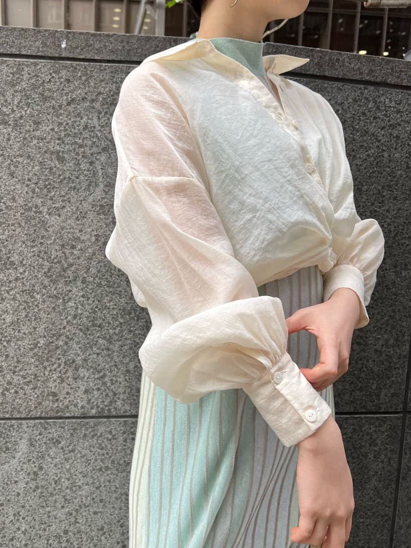 ホワイト系のショルダーバッグ、ベージュ系のブーツ、グリーン系のワンピースを着用したレディースの春コーディネートの5枚目の写真