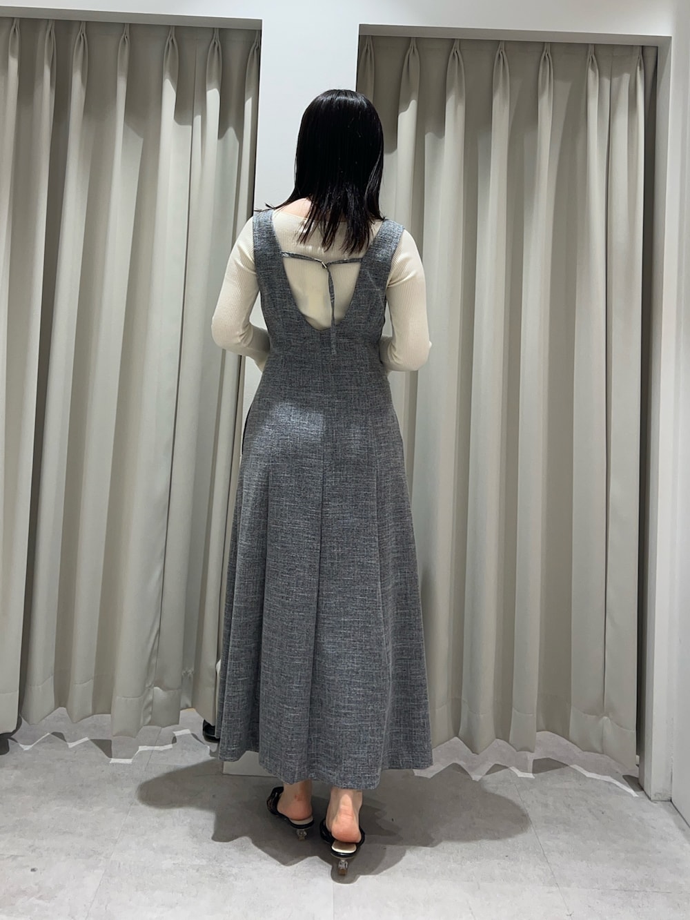 ホワイト系のニット/セーター、グレー系のジャンパースカート、ブラック系のサンダルを着用したレディースの春コーディネートの3枚目の写真
