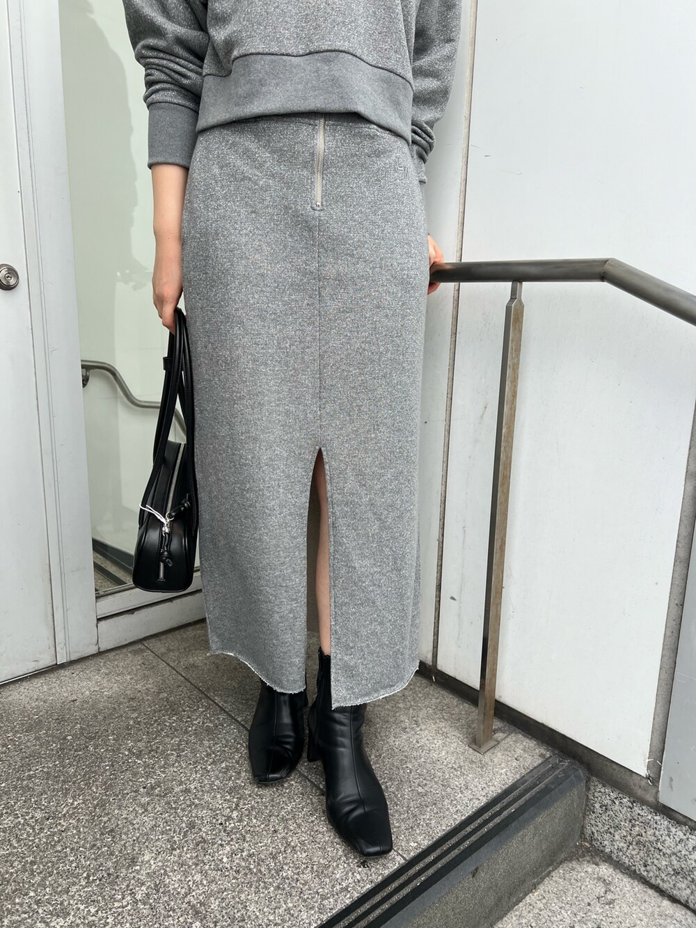 ブラック系のブーツ、グレー系のスカート、グレー系のスウェットを着用したレディースの秋コーディネートの7枚目の写真