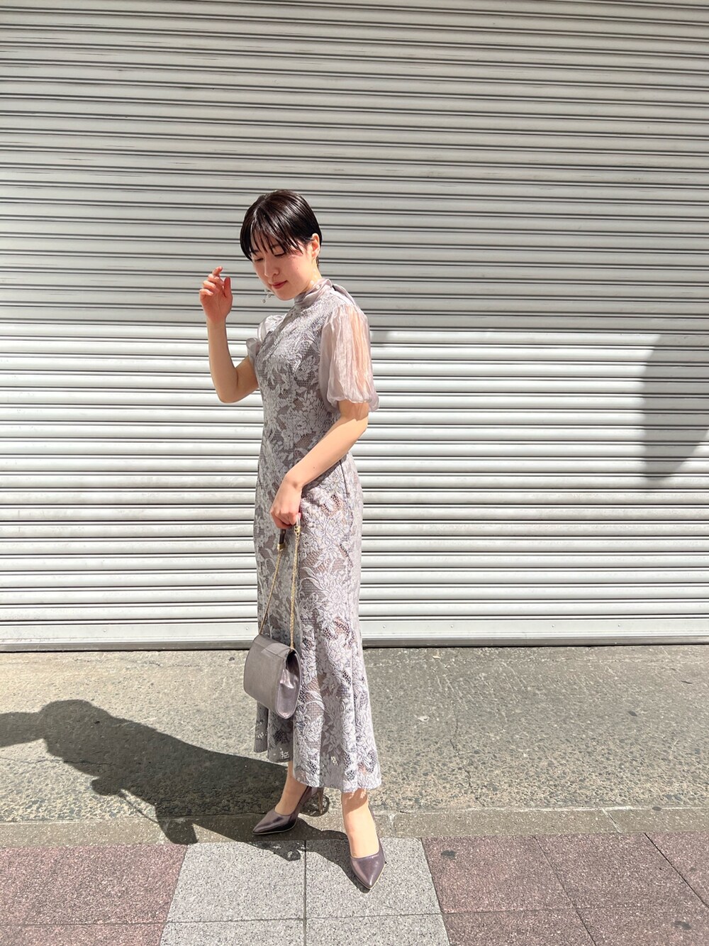 ブルー系のノーカラーコート、シルバー系のパンプス、シルバー系のクラッチバッグを着用したレディースの春コーディネートの4枚目の写真