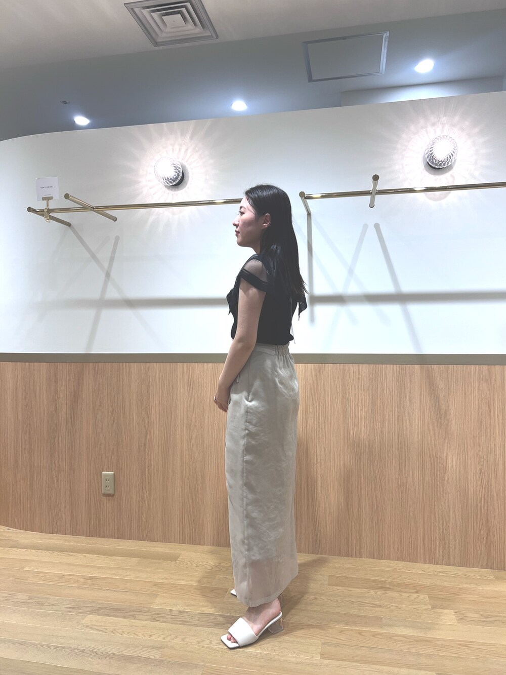 ブラック系のニット/セーター、ホワイト系のスカート、ホワイト系のサンダルを着用したレディースの春コーディネートの2枚目の写真