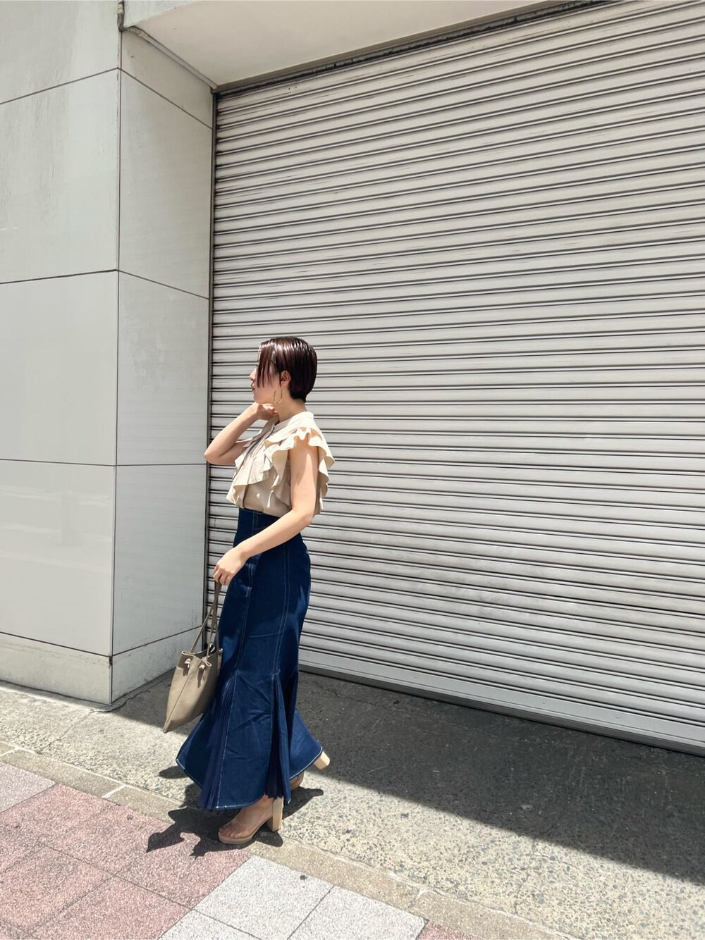 ベージュ系のハンドバッグ、ブルー系のスカート、その他のパンプスを着用したレディースの春コーディネートの2枚目の写真