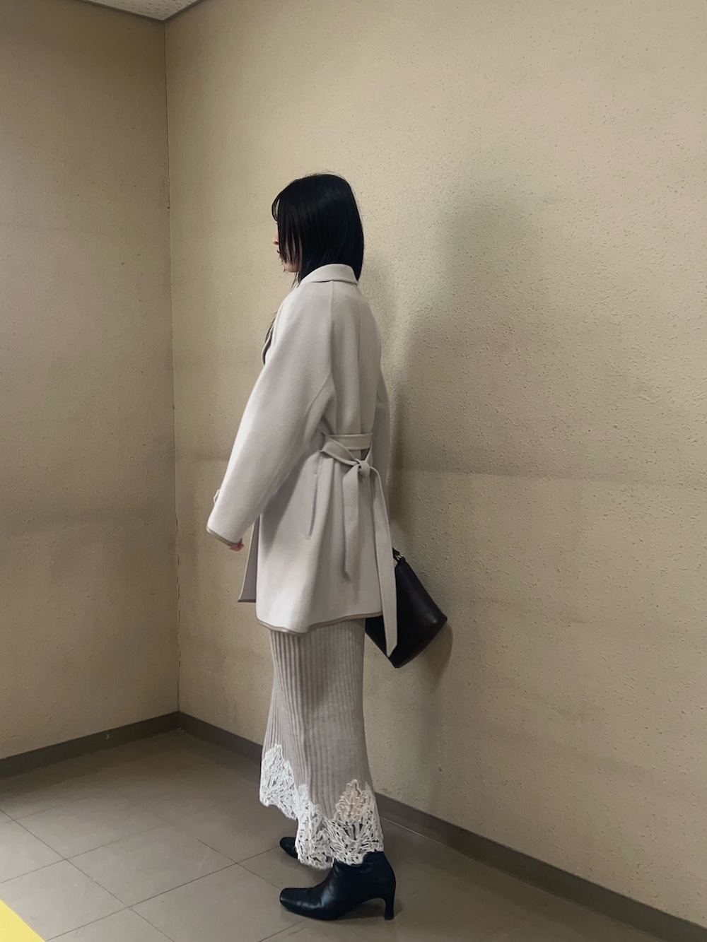 ブラック系のブーツ、ベージュ系のワンピース、ホワイト系のその他アウターを着用したレディースの秋コーディネートの2枚目の写真