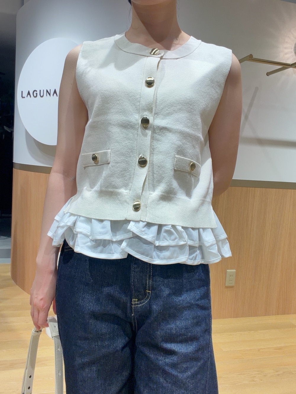 ホワイト系のニット/セーター、オレンジ系のサンダル、ブルー系のデニムパンツを着用したレディースの夏コーディネートの4枚目の写真