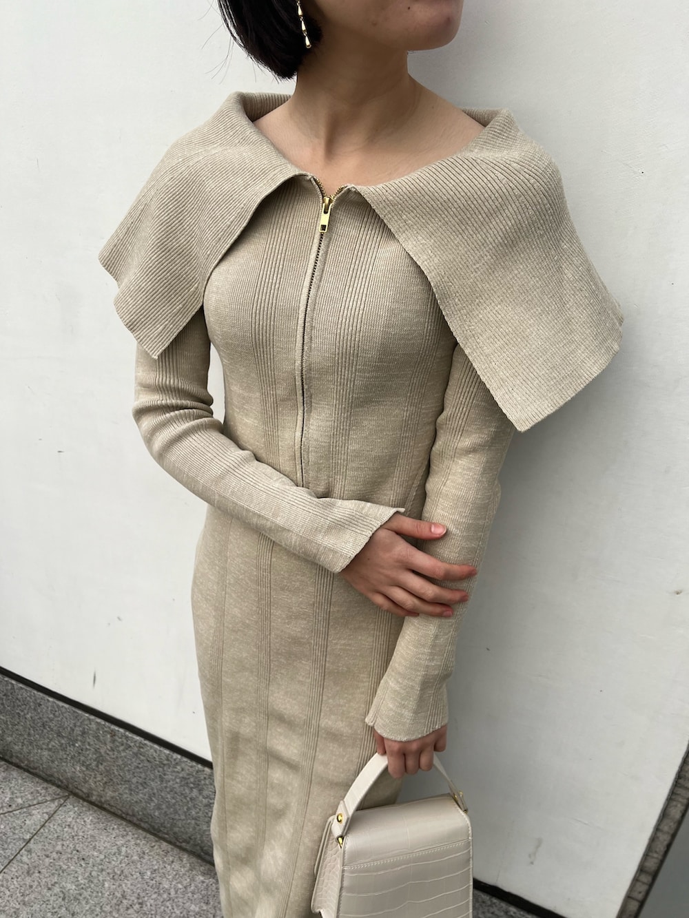 ホワイト系のパンプス、ベージュ系のワンピース、ホワイト系のショルダーバッグを着用したレディースの春コーディネートの3枚目の写真