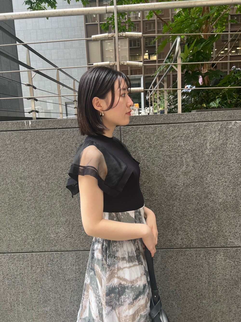 ブラック系のニット/セーター、グレー系のスカート、ブラック系のショルダーバッグを着用したレディースの春コーディネートの4枚目の写真