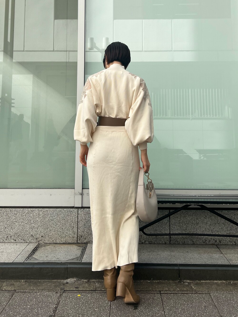 ホワイト系のハンドバッグ、ベージュ系のブーツ、ホワイト系のワンピースを着用したレディースの冬コーディネートの2枚目の写真