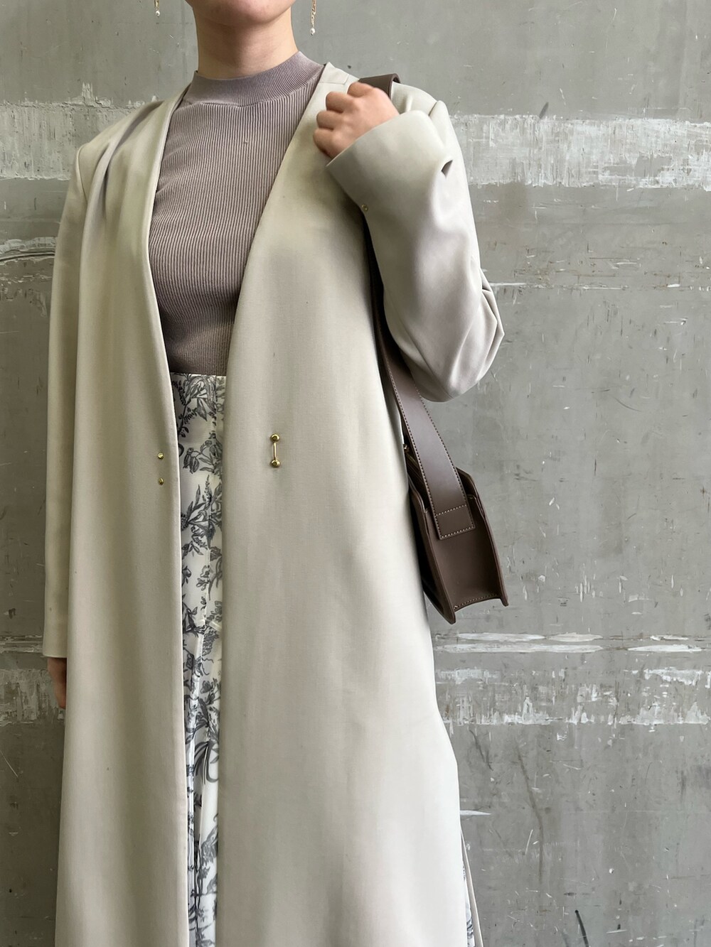 ベージュ系のノーカラーコート、ホワイト系のスカート、ベージュ系のサンダルを着用したレディースの冬コーディネートの4枚目の写真