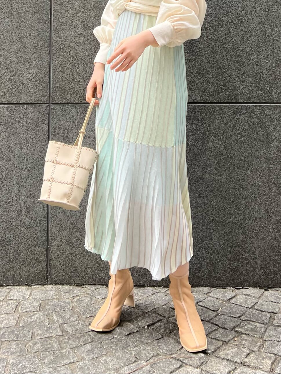 ホワイト系のショルダーバッグ、ベージュ系のブーツ、グリーン系のワンピースを着用したレディースの春コーディネートの6枚目の写真