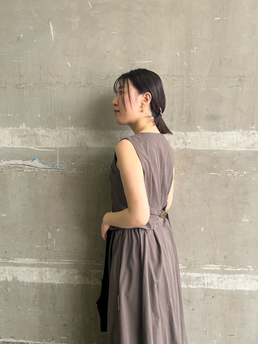 グレー系のワンピース、ブラック系のハンドバッグ、ブラック系のサンダルを着用したレディースの夏コーディネートの4枚目の写真