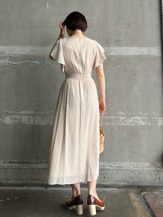 ホワイト系のワンピース、ブラウン系のパンプス、オレンジ系のショルダーバッグを着用したレディースの春コーディネートの2枚目の写真