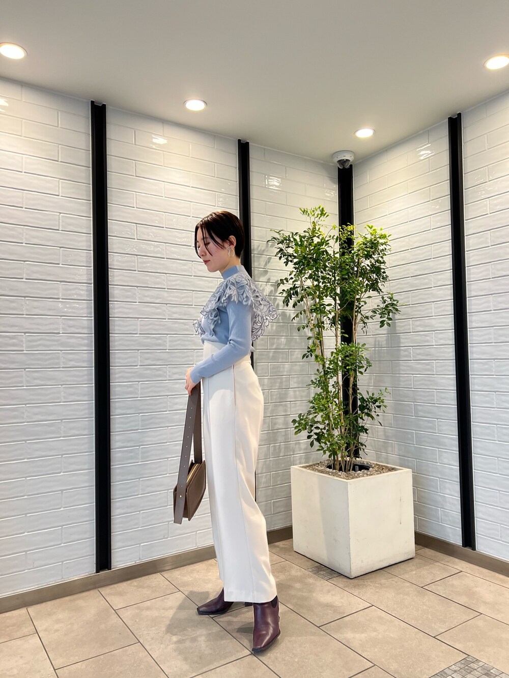 ベージュ系のノーカラーコート、ベージュ系のショルダーバッグ、レッド系のブーツを着用したレディースの冬コーディネートの7枚目の写真