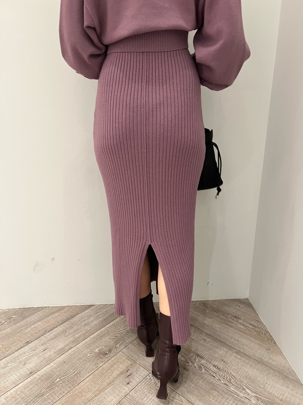 レッド系のブーツ、ブラック系のハンドバッグ、パープル系のワンピースを着用したレディースの冬コーディネートの8枚目の写真