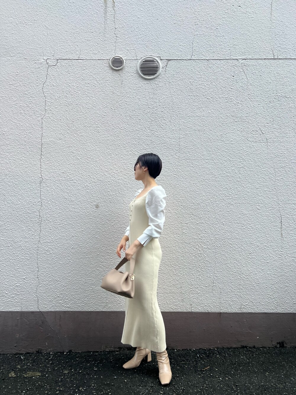 ベージュ系のハンドバッグ、ベージュ系のブーツ、ホワイト系のワンピースを着用したレディースの秋コーディネートの2枚目の写真