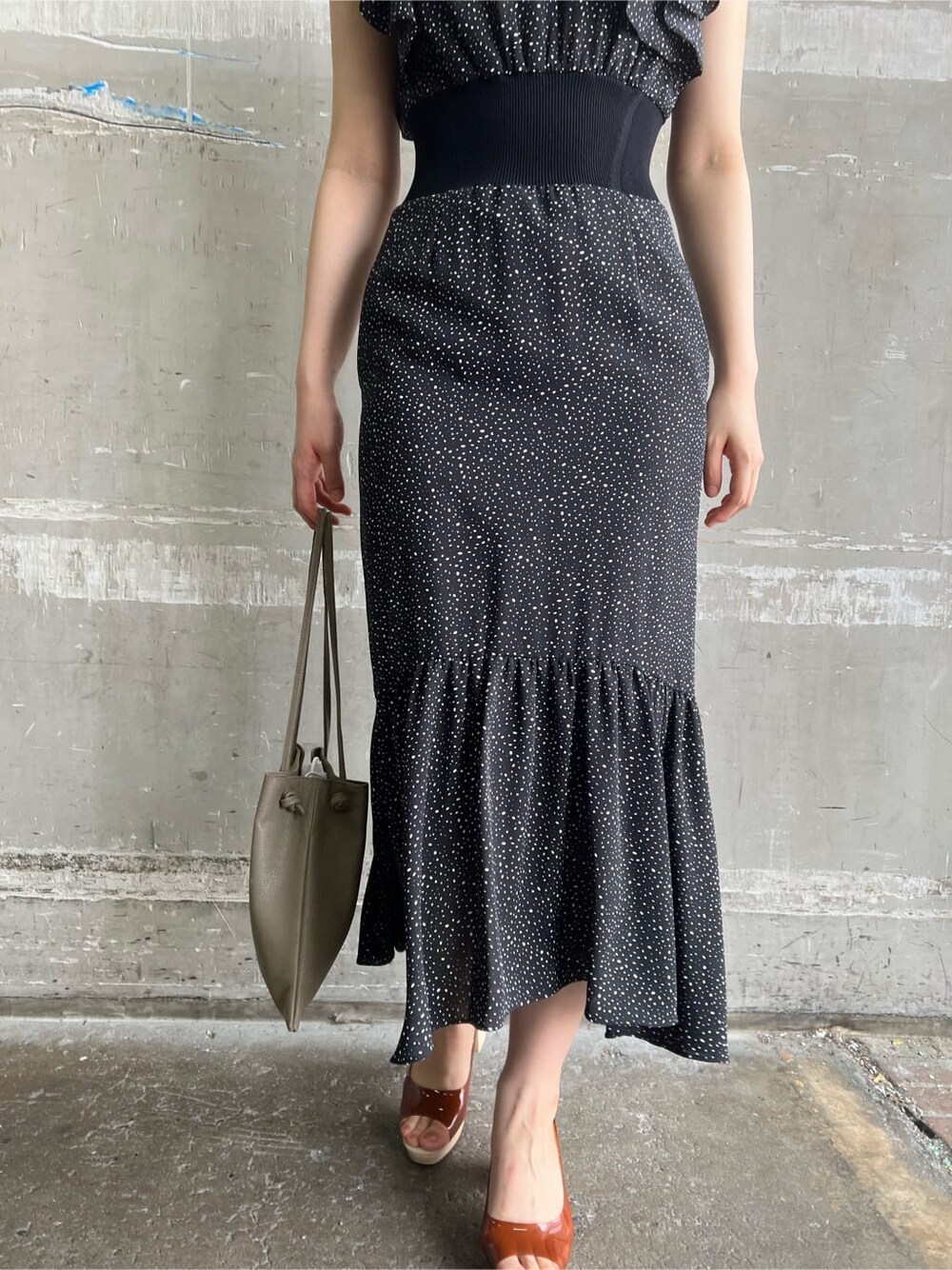 ベージュ系のハンドバッグ、ブラウン系のパンプス、ブラック系のワンピースを着用したレディースの夏コーディネートの8枚目の写真