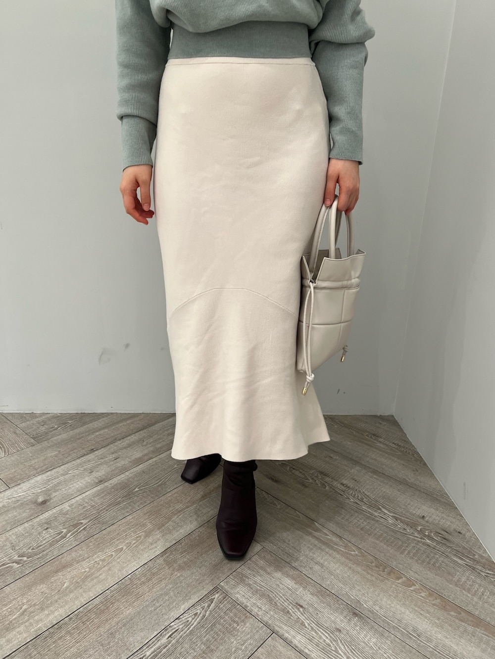 レッド系のブーツ、ホワイト系のハンドバッグ、ホワイト系のスカートを着用したレディースの冬コーディネートの7枚目の写真