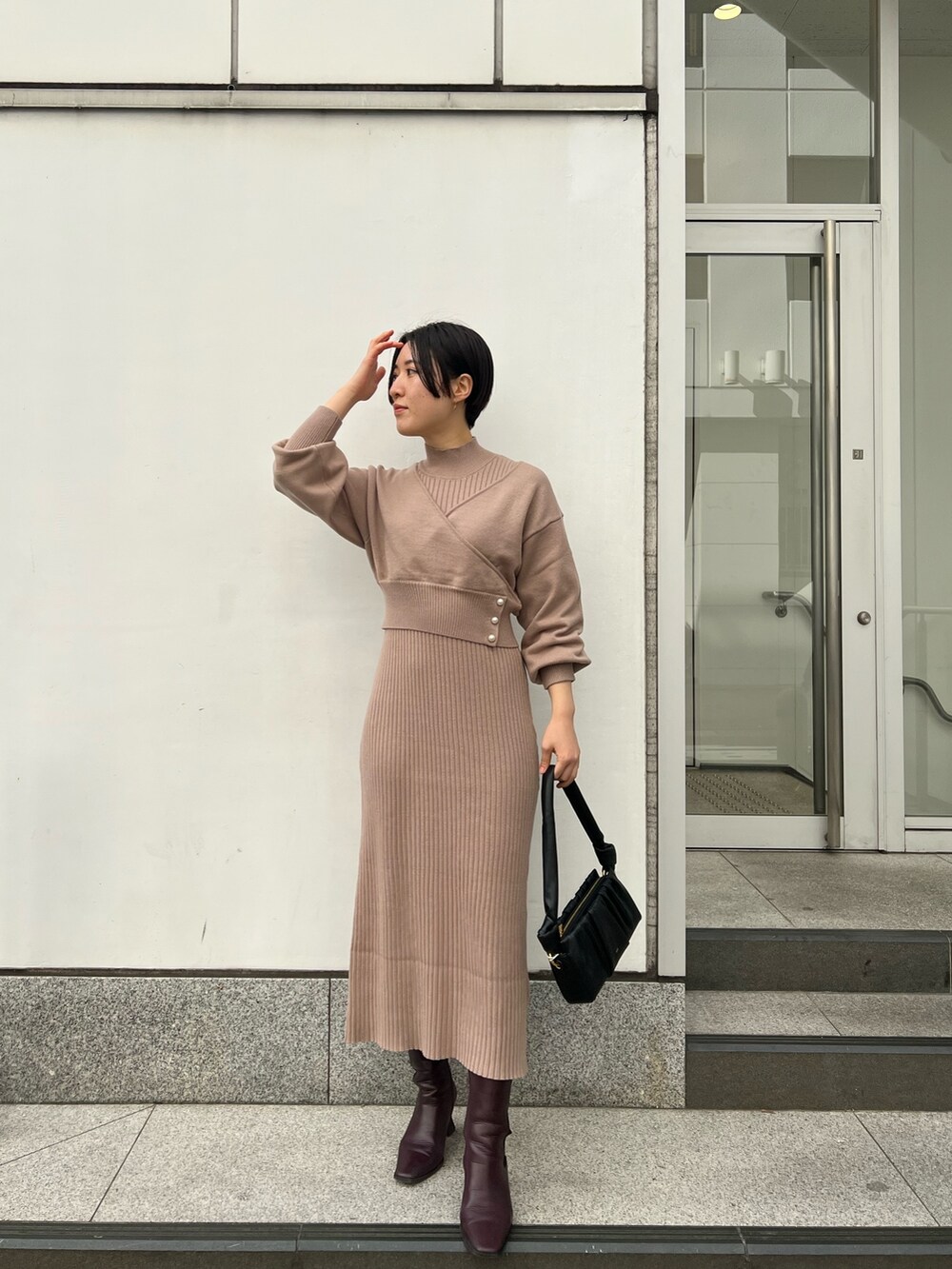 レッド系のブーツ、ブラック系のハンドバッグ、ベージュ系のワンピースを着用したレディースの冬コーディネートの5枚目の写真