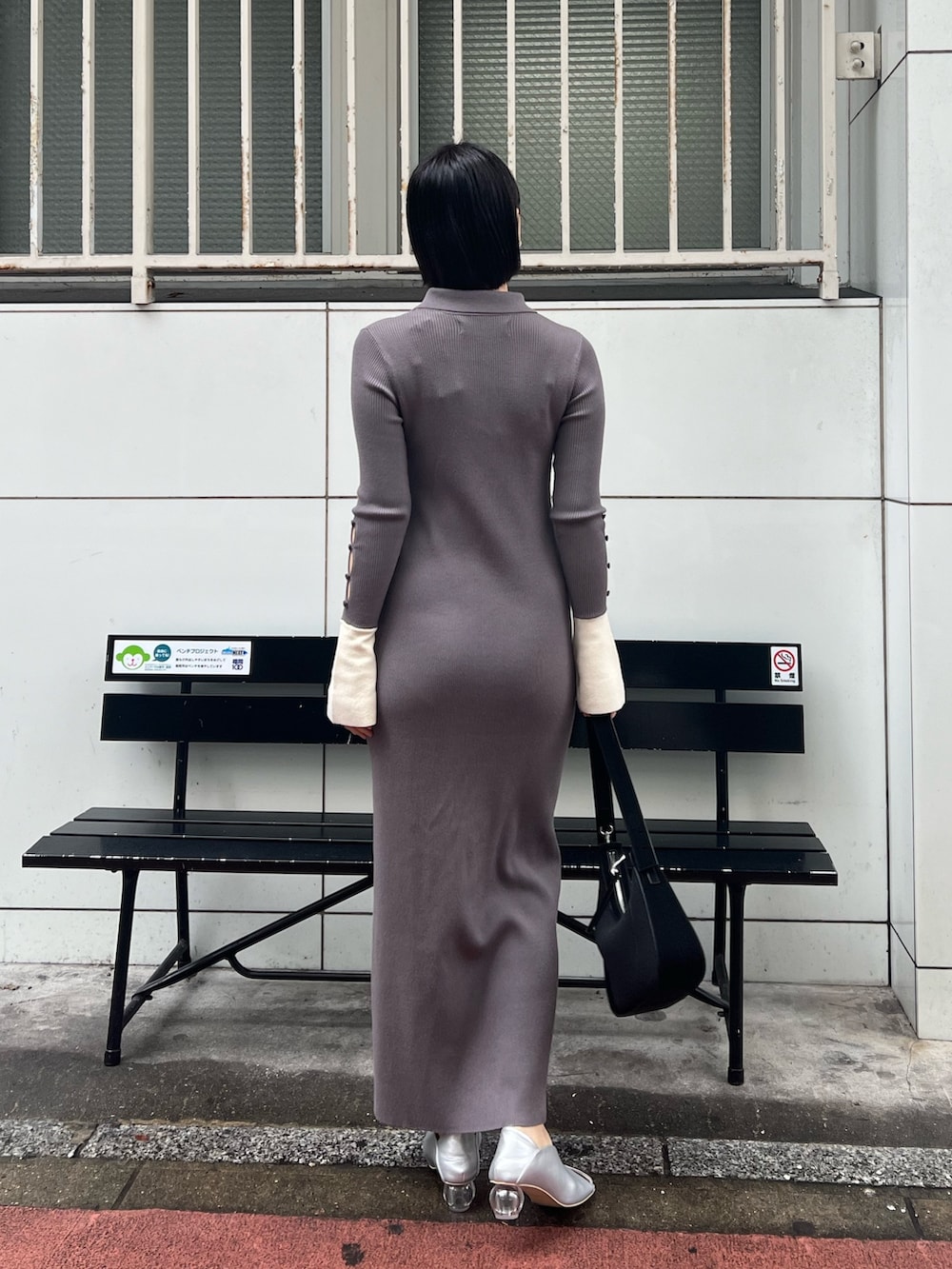 ブラック系のハンドバッグ、グレー系のワンピース、シルバー系のパンプスを着用したレディースの冬コーディネートの2枚目の写真