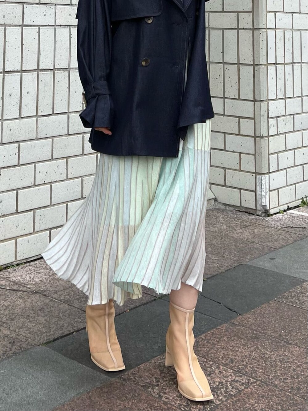 ベージュ系のブーツ、ブルー系のトレンチコート、グリーン系のワンピースを着用したレディースの春コーディネートの6枚目の写真