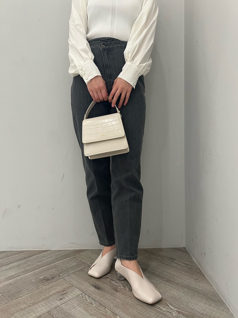 ホワイト系のトレンチコート、ホワイト系のニット/セーター、ブラック系のデニムパンツを着用したレディースの冬コーディネートの8枚目の写真