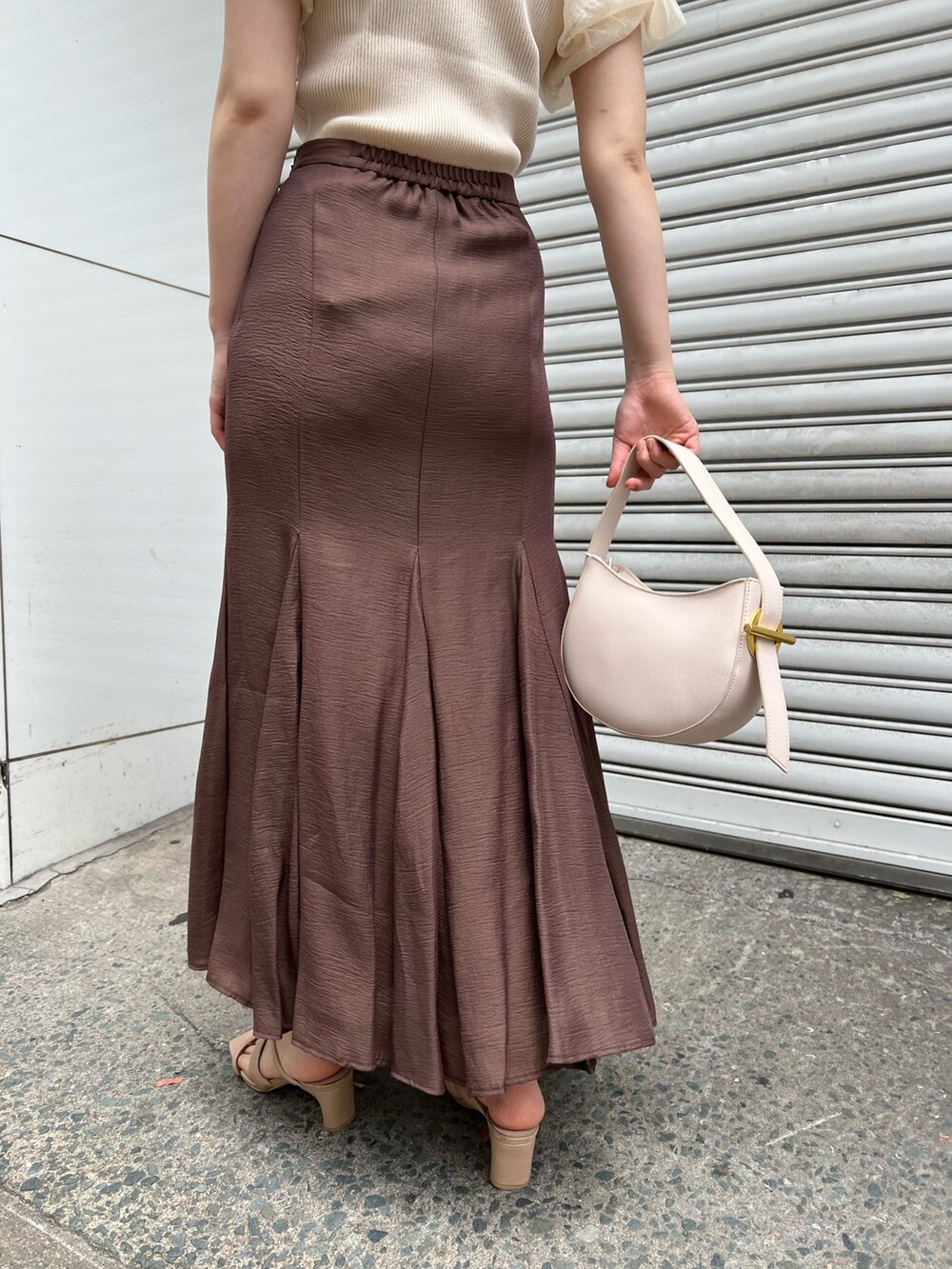 ベージュ系のサンダル、ブラウン系のスカート、ホワイト系のハンドバッグを着用したレディースの夏コーディネートの9枚目の写真