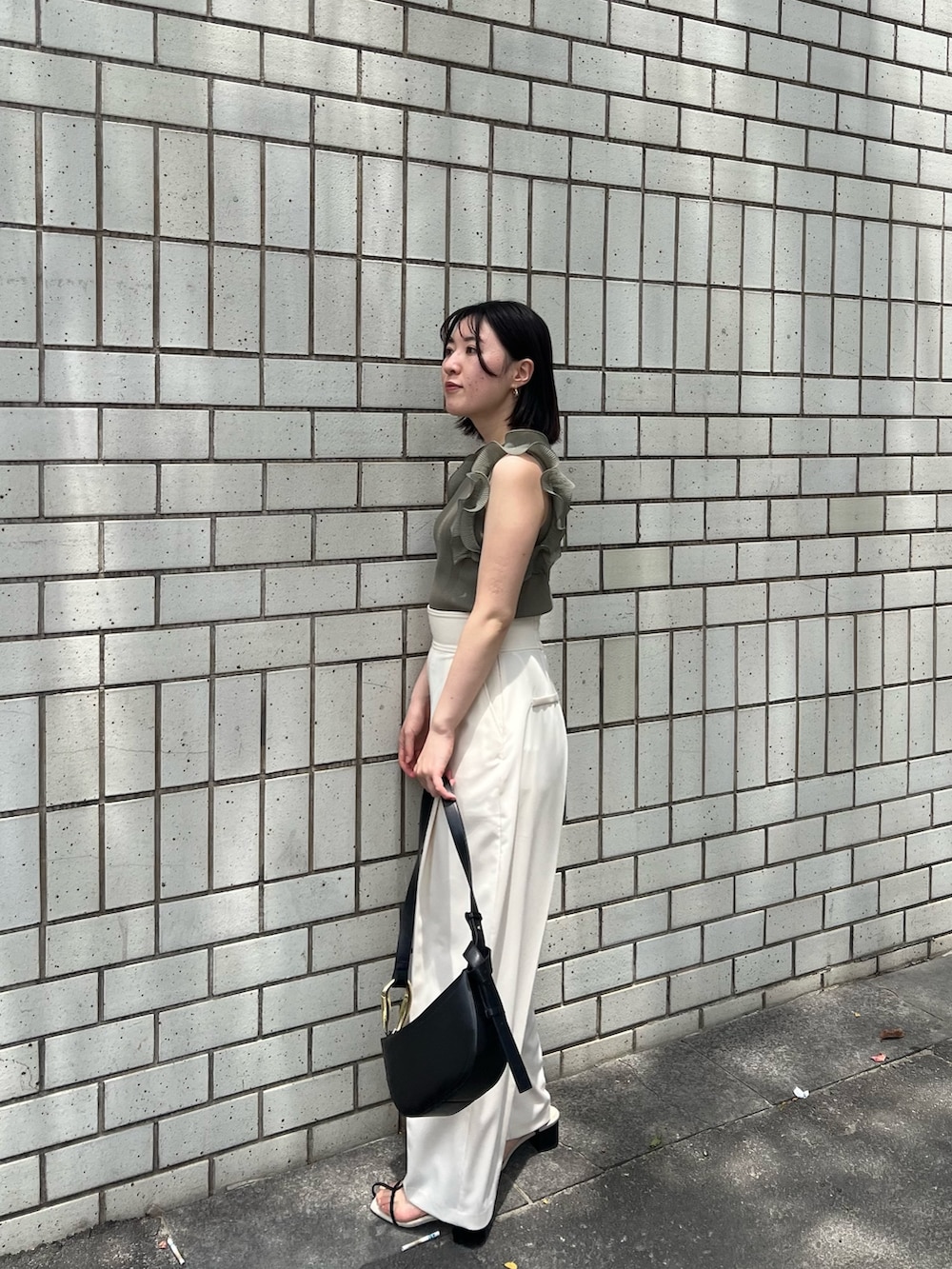 グリーン系のニット/セーター、ホワイト系のその他パンツ、ブラック系のサンダルを着用したレディースの春コーディネートの2枚目の写真