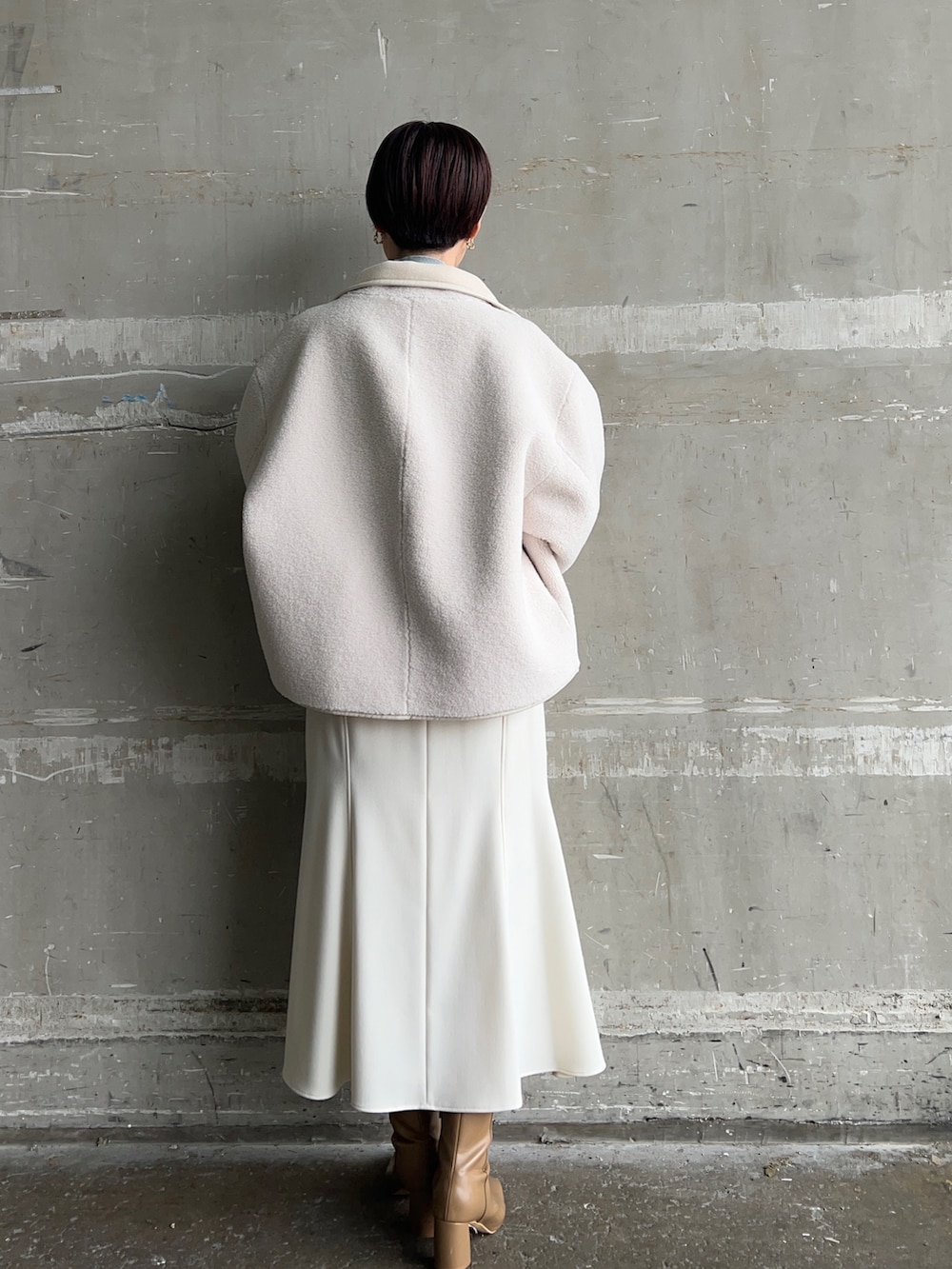 ベージュ系のブーツ、ホワイト系のハンドバッグ、ホワイト系のムートンコートを着用したレディースの秋コーディネートの3枚目の写真