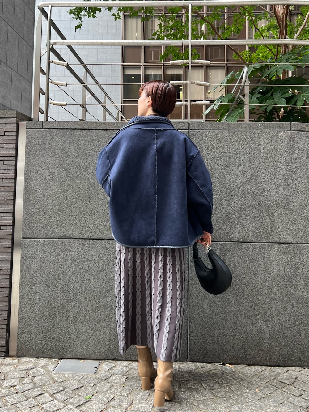 ベージュ系のブーツ、ブラック系のハンドバッグ、ブルー系のムートンコートを着用したレディースの秋コーディネートの2枚目の写真