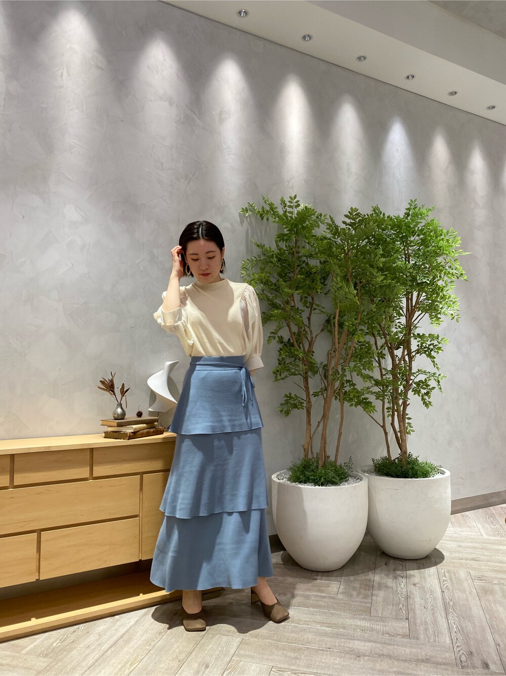 ブルー系のスカート、ホワイト系のニット/セーター、ベージュ系のサンダルを着用したレディースの春コーディネートの3枚目の写真