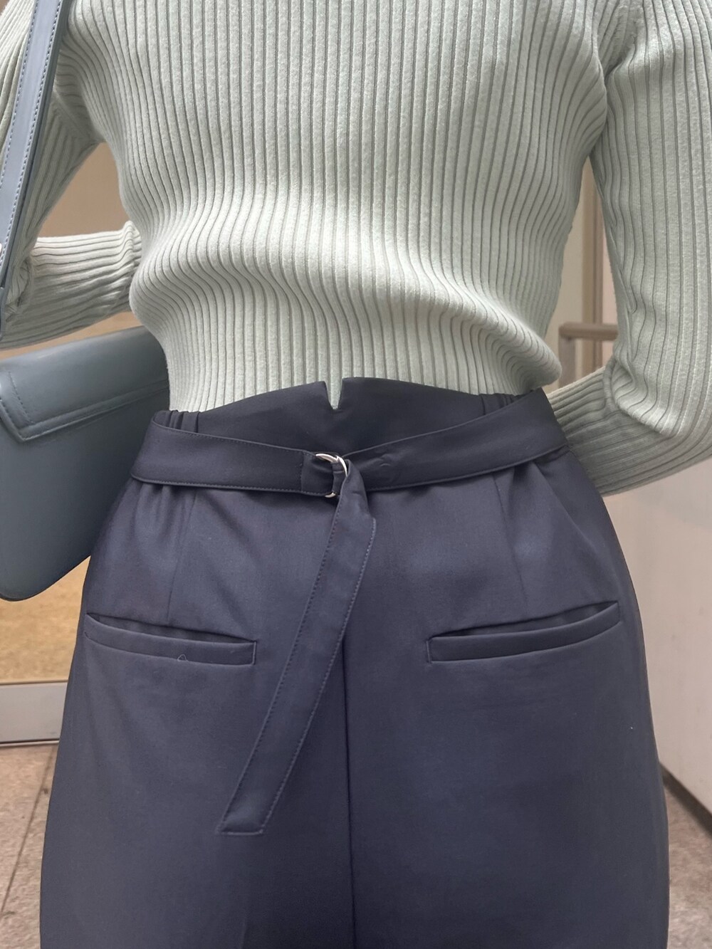 ブルー系のショルダーバッグ、グレー系のスラックス、グリーン系のニット/セーターを着用したレディースの冬コーディネートの8枚目の写真