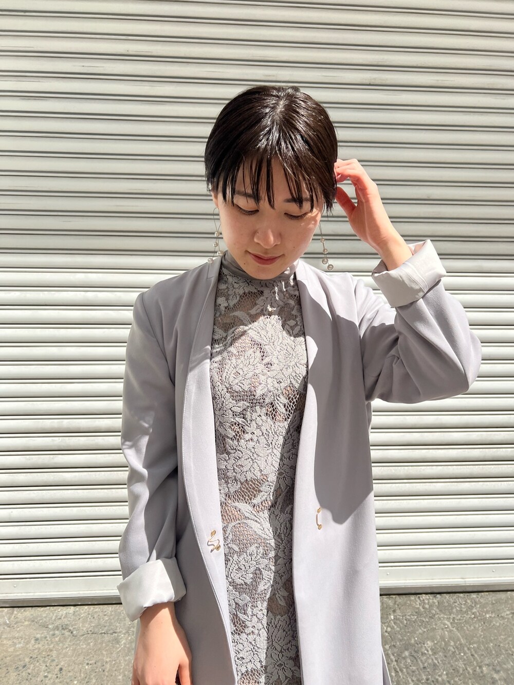 ブルー系のノーカラーコート、シルバー系のパンプス、シルバー系のクラッチバッグを着用したレディースの春コーディネートの2枚目の写真