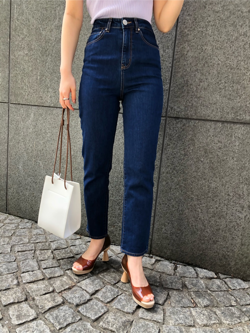 ブラウン系のパンプス、ブルー系のデニムパンツ、ホワイト系のハンドバッグを着用したレディースの春コーディネートの6枚目の写真