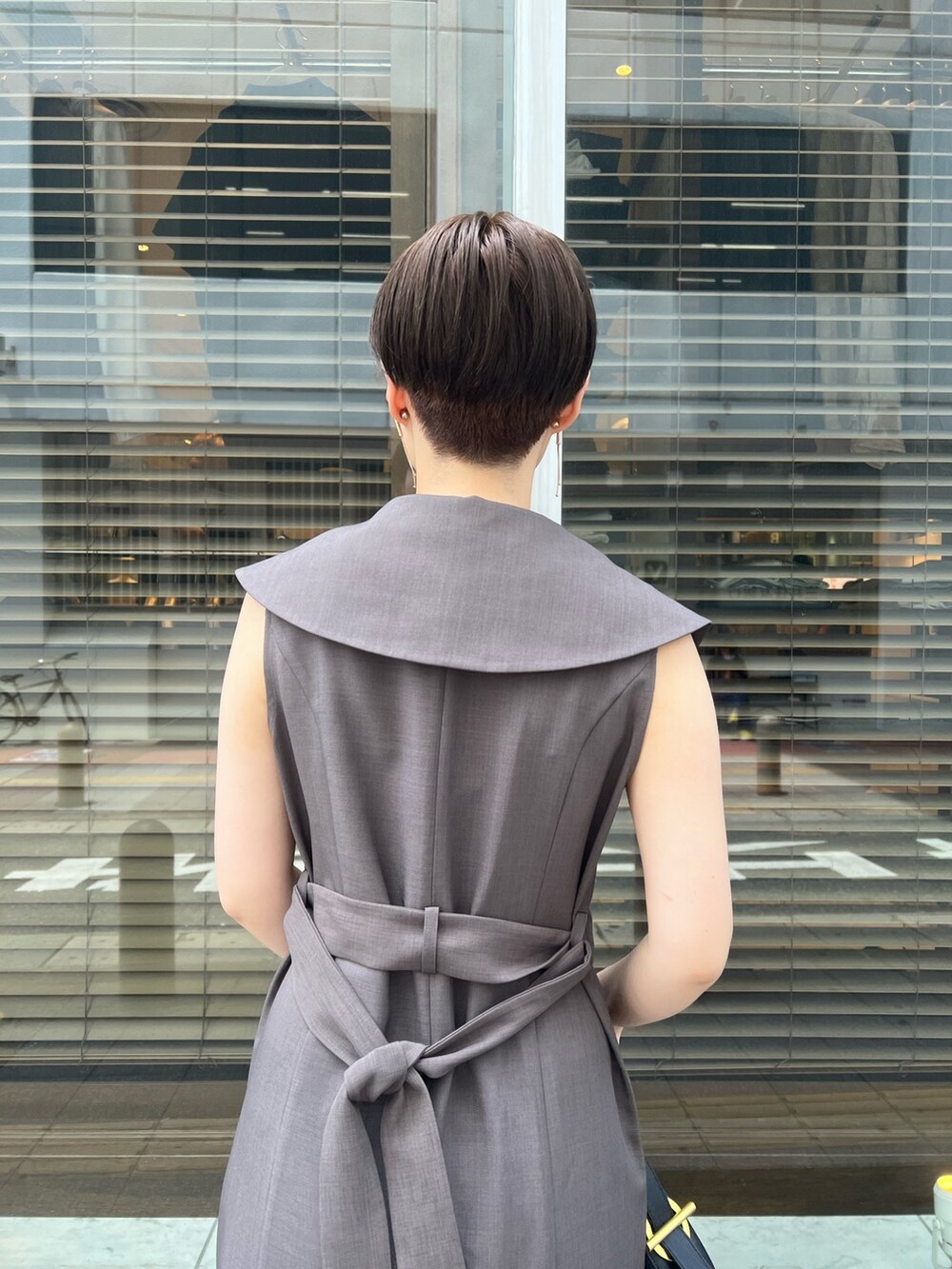 グレー系のワンピース、ブラック系のサンダル、ブラック系のハンドバッグを着用したレディースの夏コーディネートの6枚目の写真