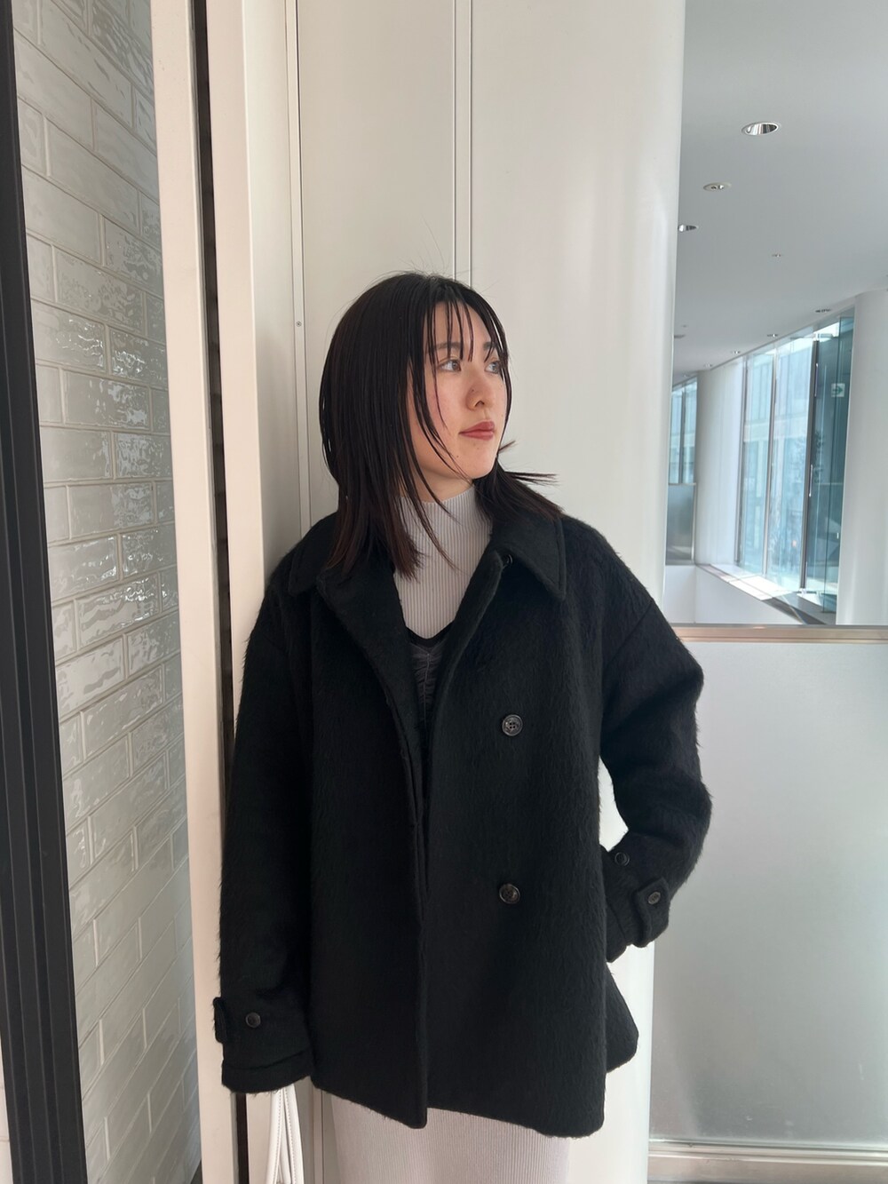 ブラック系のステンカラーコート、ブルー系のワンピース、ブラック系のブーツを着用したレディースの冬コーディネートの4枚目の写真