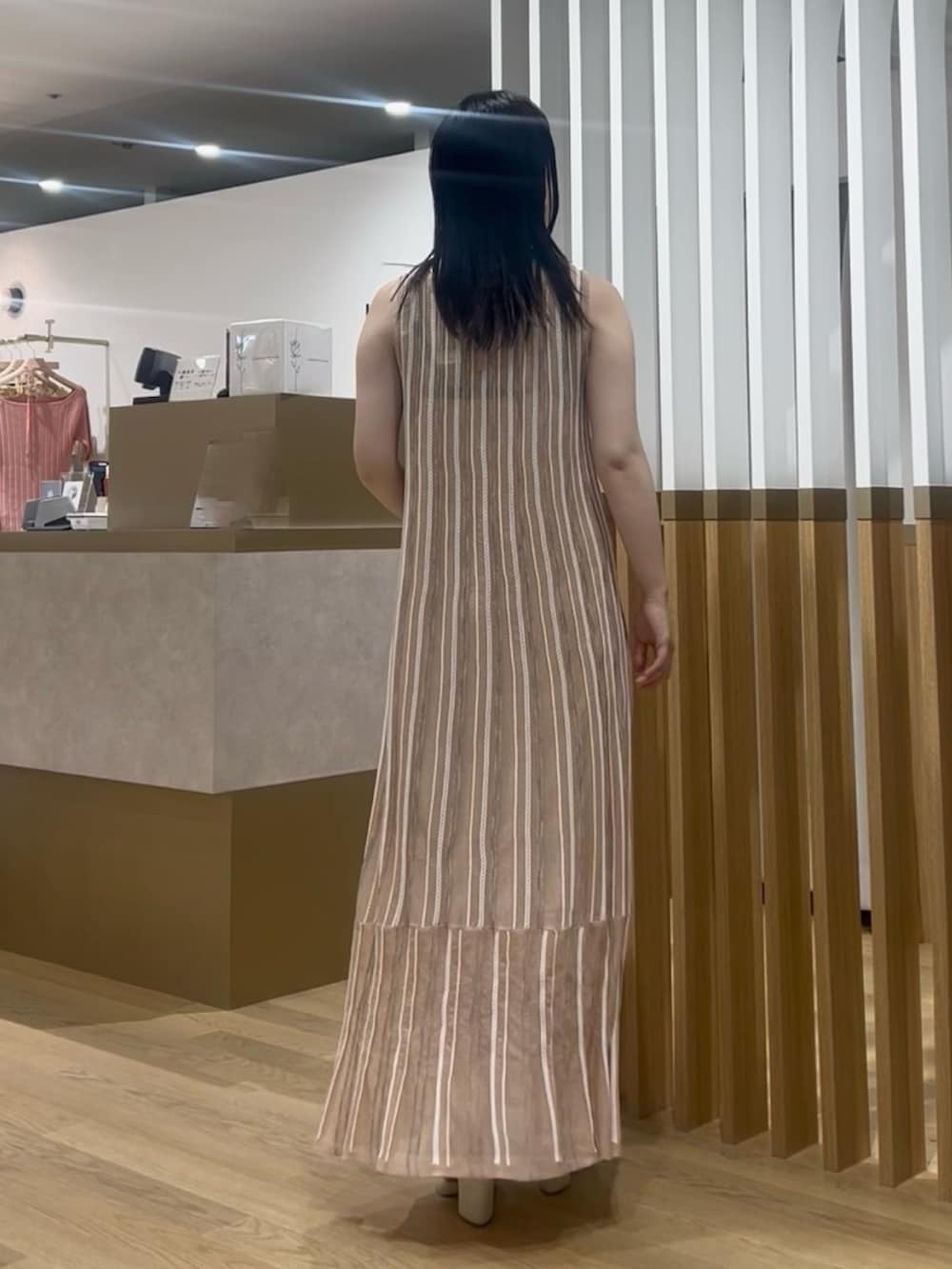 ブラウン系のハンドバッグ、オレンジ系のワンピース、ホワイト系のサンダルを着用したレディースの春コーディネートの3枚目の写真