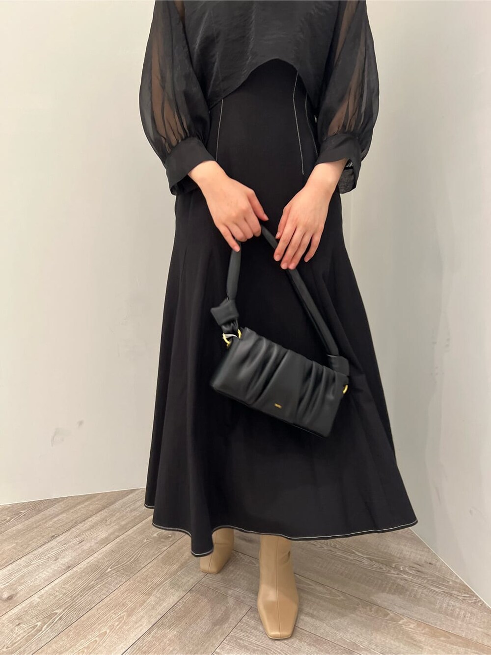 ベージュ系のブーツ、ブラック系のワンピース、ブラック系のハンドバッグを着用したレディースの秋コーディネートの7枚目の写真