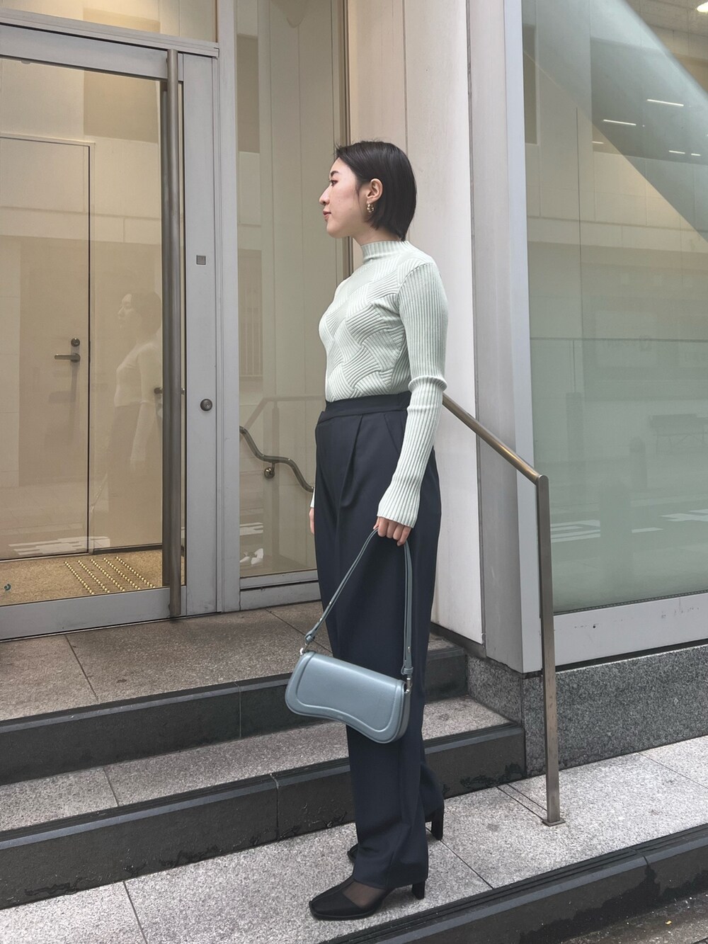 ブルー系のショルダーバッグ、グレー系のスラックス、グリーン系のニット/セーターを着用したレディースの冬コーディネートの2枚目の写真